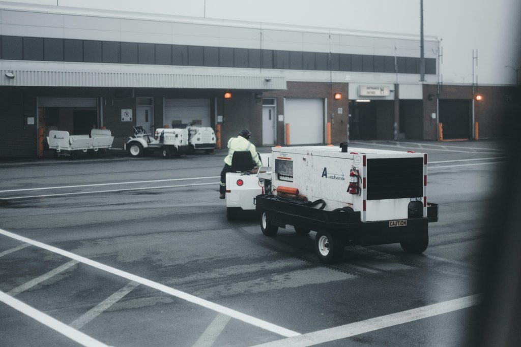 An airport vehicle towing equipment on a rainy day, highlighting airport operations and maintenance.